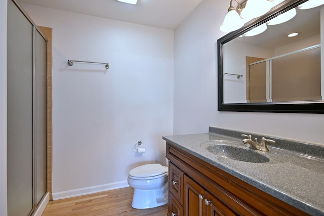 bathroom with vanity, a shower stall, wood finished floors, and toilet