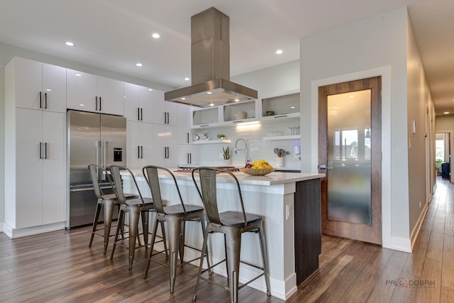2860 N Milwaukee Ave Unit 2S, Chicago, IL 60618 - kitchen featuring built in fridge, island exhaust hood, dark wood finished floors, open shelves, and an island with sink