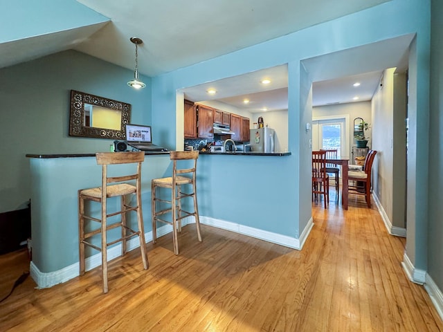 1703 S Ruble St, Chicago, IL 60616 - kitchen featuring freestanding refrigerator, under cabinet range hood, dark countertops, light wood-type flooring, and brown cabinets