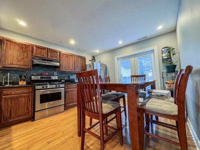 1703 S Ruble St, Chicago, IL 60616 - kitchen with stainless steel appliances, under cabinet range hood, light wood finished floors, dark countertops, and decorative backsplash
