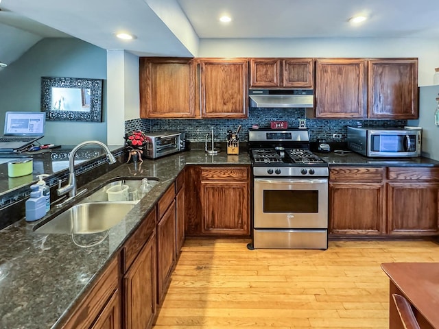 1703 S Ruble St, Chicago, IL 60616 - kitchen featuring stainless steel appliances, under cabinet range hood, a sink, light wood finished floors, and dark stone countertops