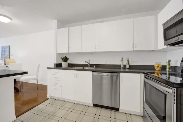 405 N Wabash Ave Unit 1002, Chicago, IL 60611 - kitchen with appliances with stainless steel finishes, a sink, light floors, white cabinetry, and dark countertops