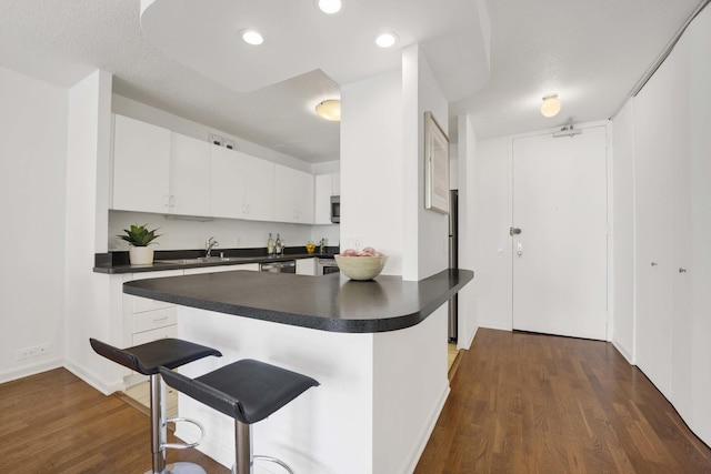 405 N Wabash Ave Unit 1002, Chicago, IL 60611 - kitchen with dark countertops, dark wood finished floors, white cabinets, appliances with stainless steel finishes, and recessed lighting