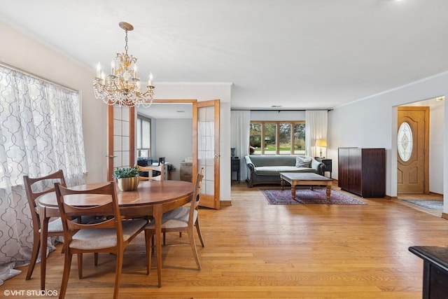 dining area featuring a chandelier, light wood finished floors, and ornamental molding