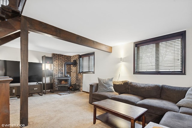 living room with a wood stove, carpet flooring, plenty of natural light, and beamed ceiling