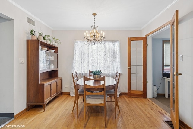 dining area featuring light wood finished floors, a chandelier, crown molding, and baseboards