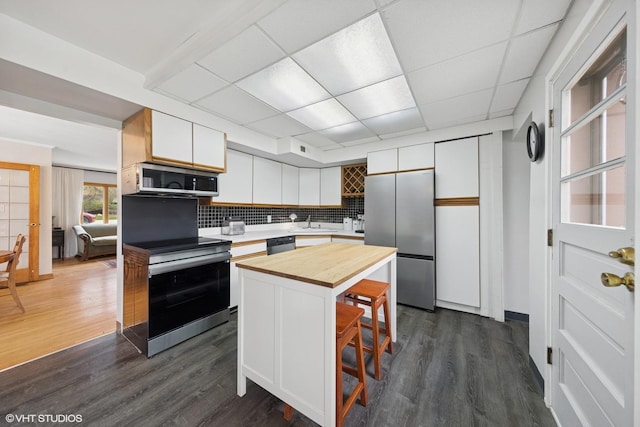 kitchen featuring stainless steel appliances, butcher block countertops, a sink, white cabinetry, and dark wood finished floors