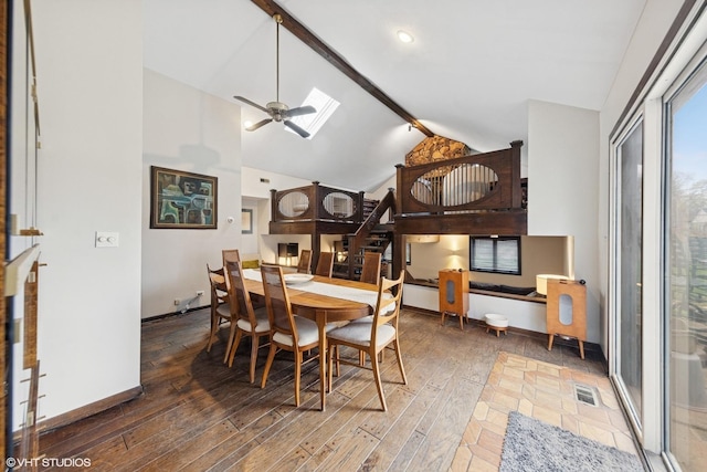dining space with a skylight, beam ceiling, hardwood / wood-style floors, high vaulted ceiling, and ceiling fan