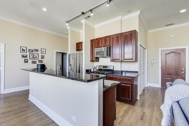 4440 N Kedzie Ave Unit 401, Chicago, IL 60625 - kitchen with appliances with stainless steel finishes, rail lighting, baseboards, a kitchen island with sink, and light wood finished floors