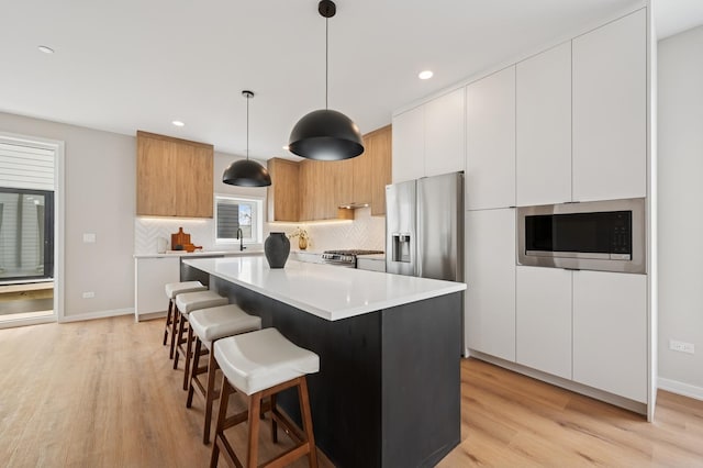 944 Beloit Ave Unit 2, Forest Park, IL 60130 - kitchen with appliances with stainless steel finishes, light wood-style floors, modern cabinets, decorative backsplash, and a center island