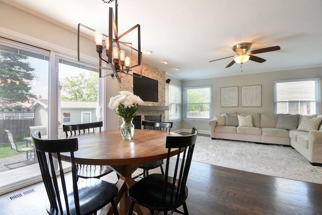 1112 Laurel Ln, Gurnee, IL 60031 - dining room featuring wood finished floors, a large fireplace, ceiling fan, a chandelier, and crown molding
