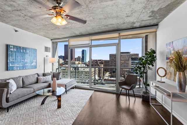 living room featuring a view of skyline, a wall of windows, wood finished floors, and a ceiling fan