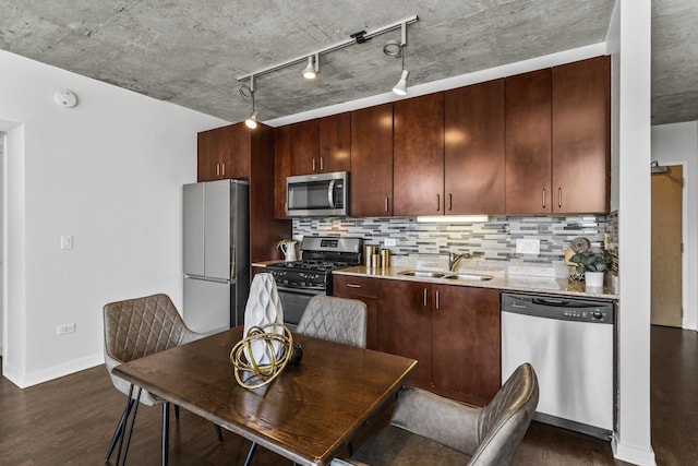 kitchen featuring appliances with stainless steel finishes, a sink, track lighting, and decorative backsplash