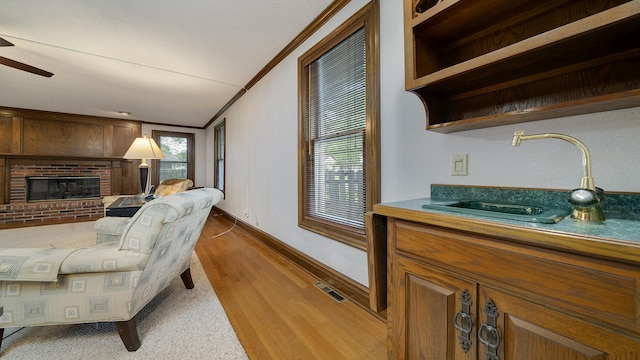 321 E Chamberlin St, Dixon, IL 61021 - living room with a brick fireplace, crown molding, a ceiling fan, wood finished floors, and baseboards