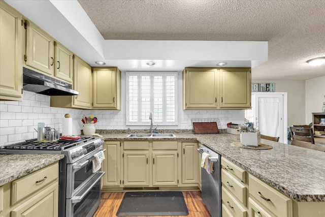 705 Northridge Dr, Mahomet, IL 61853 - kitchen featuring appliances with stainless steel finishes, under cabinet range hood, a peninsula, a textured ceiling, and decorative backsplash