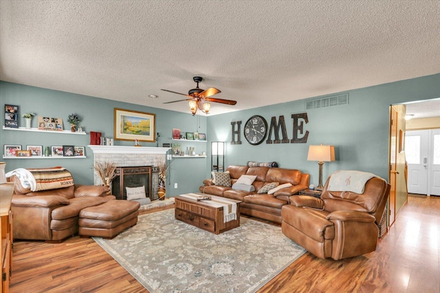 705 Northridge Dr, Mahomet, IL 61853 - living room with wood finished floors, a textured ceiling, ceiling fan, and a fireplace