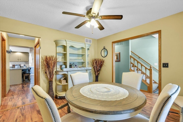 705 Northridge Dr, Mahomet, IL 61853 - dining area featuring wood finished floors, ceiling fan, stairway, and a textured ceiling