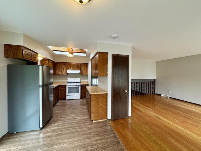 16104 Oak Ave, Oak Forest, IL 60452 - kitchen featuring white gas range, freestanding refrigerator, light wood-style floors, a skylight, and light countertops