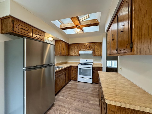 16104 Oak Ave, Oak Forest, IL 60452 - kitchen featuring freestanding refrigerator, white range with gas stovetop, under cabinet range hood, a skylight, and light countertops