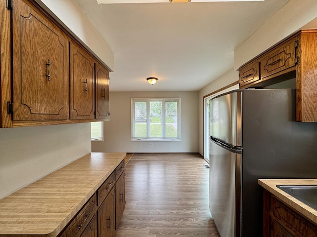 16104 Oak Ave, Oak Forest, IL 60452 - kitchen featuring freestanding refrigerator, light wood-style flooring, light countertops, and brown cabinets