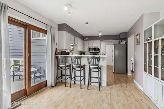 1140 Catalpa Ln, Naperville, IL 60540 - kitchen with appliances with stainless steel finishes, a peninsula, light wood-style floors, light countertops, and baseboards