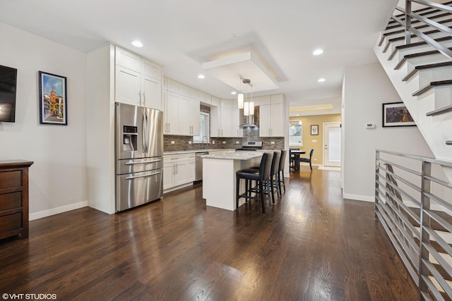 3019 N Allen Ave, Chicago, IL 60618 - kitchen with appliances with stainless steel finishes, a kitchen bar, dark wood-style flooring, tasteful backsplash, and recessed lighting