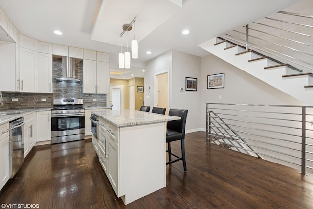 3019 N Allen Ave, Chicago, IL 60618 - kitchen featuring appliances with stainless steel finishes, wall chimney range hood, dark wood-type flooring, a sink, and a kitchen bar