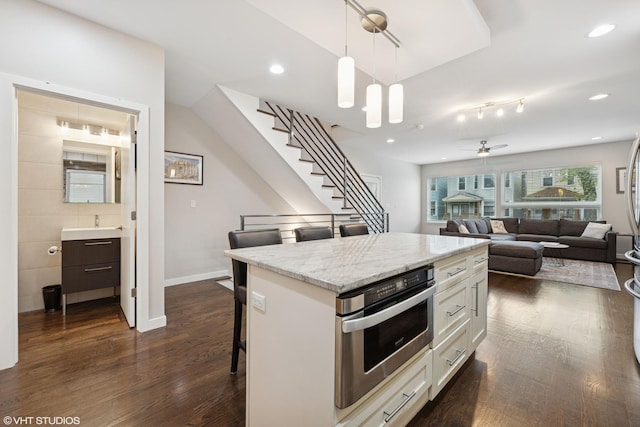 3019 N Allen Ave, Chicago, IL 60618 - kitchen featuring dark wood-style floors, decorative light fixtures, white cabinets, oven, and a breakfast bar