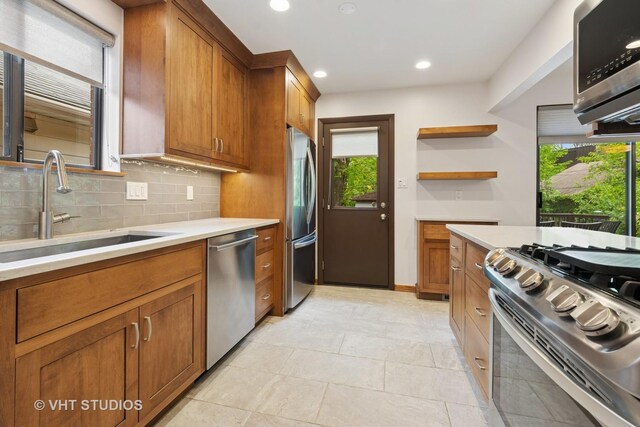 1809 Grant St, Evanston, IL 60201 - kitchen featuring stainless steel appliances, a sink, a peninsula, brown cabinets, and tasteful backsplash