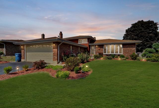510 W Millns Ct, Addison, IL 60101 - tri-level home with asphalt driveway, a garage, brick siding, a lawn, and a chimney