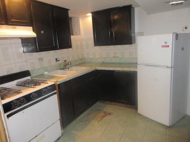 2311 N Natchez Ave, Chicago, IL 60707 - kitchen with freestanding refrigerator, range with gas cooktop, under cabinet range hood, and tasteful backsplash