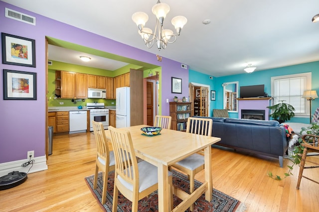 3300 Grove Ave Unit 3S, Berwyn, IL 60402 - dining room featuring light wood-style flooring, a chandelier, and a fireplace