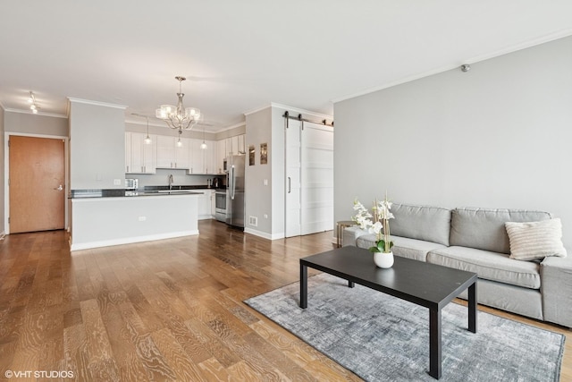 421 W Huron St Unit 1503, Chicago, IL 60654 - living room featuring ornamental molding, a chandelier, a barn door, dark wood-type flooring, and baseboards