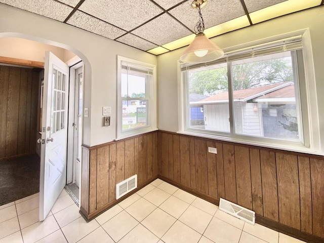 664 E 163rd St, South Holland, IL 60473 - unfurnished dining area featuring arched walkways, wainscoting, wooden walls, and light tile patterned floors