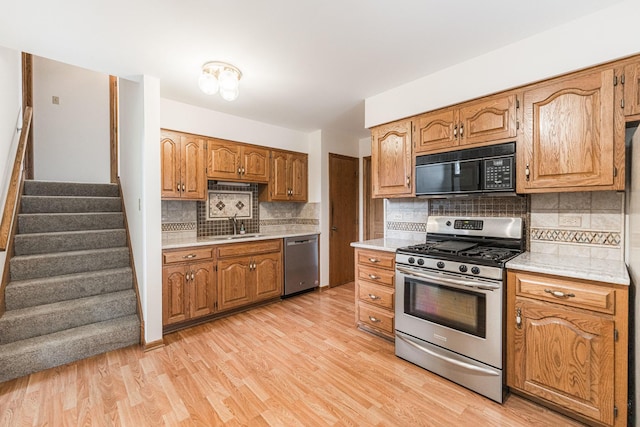 18207 Ohio Ct, Orland Park, IL 60467 - kitchen featuring stainless steel appliances, light countertops, backsplash, brown cabinetry, and light wood finished floors