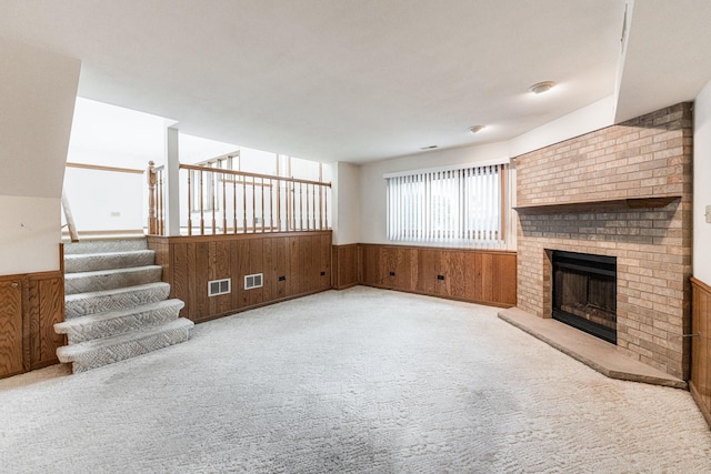 18207 Ohio Ct, Orland Park, IL 60467 - unfurnished living room featuring carpet flooring, a wainscoted wall, wooden walls, a brick fireplace, and stairs