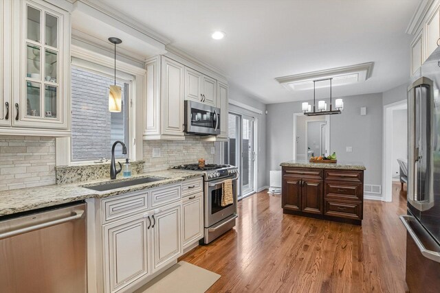 4647 N Thatcher Ave, Norridge, IL 60706 - kitchen featuring stainless steel appliances, a sink, wood finished floors, backsplash, and glass insert cabinets