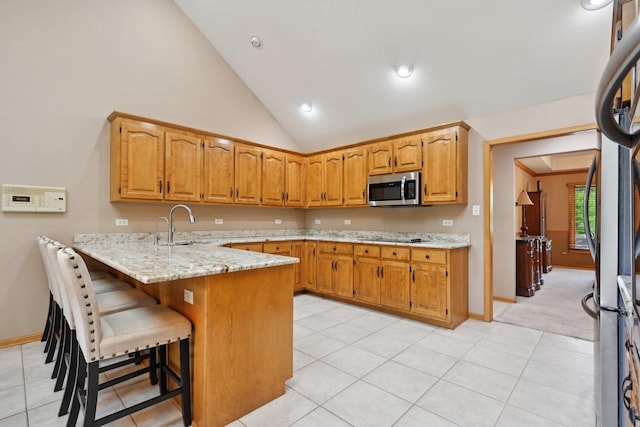 22178 Chamomile Dr, Frankfort, IL 60423 - kitchen with stainless steel microwave, a peninsula, light stone counters, a sink, and a breakfast bar