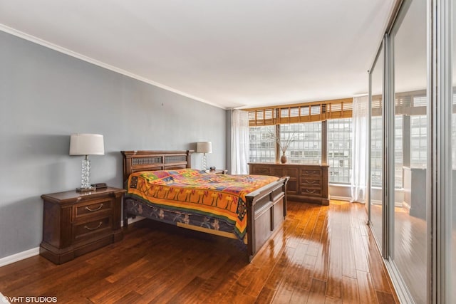 bedroom with wood-type flooring, crown molding, and baseboards