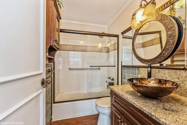 bathroom featuring crown molding, vanity, toilet, backsplash, and enclosed tub / shower combo