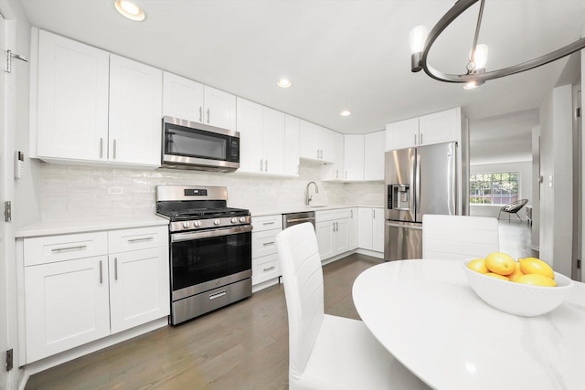 2569 Essex Dr, Northbrook, IL 60062 - kitchen with appliances with stainless steel finishes, light countertops, white cabinetry, wood finished floors, and tasteful backsplash