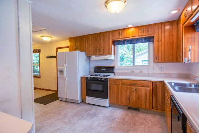1700 W William St, Champaign, IL 61821 - kitchen featuring gas range, white fridge with ice dispenser, under cabinet range hood, brown cabinets, and light countertops