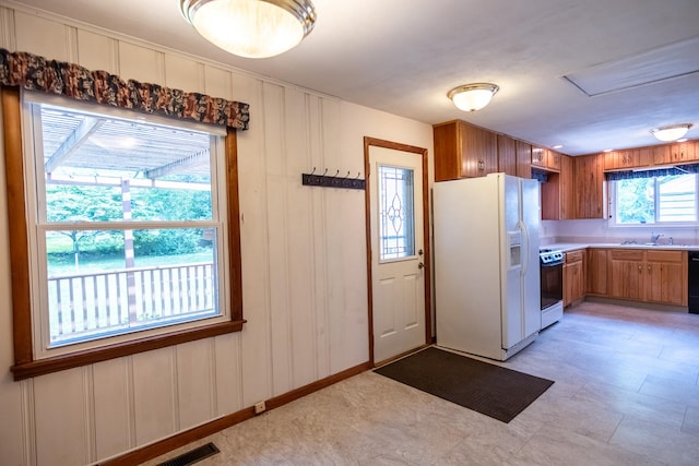 1700 W William St, Champaign, IL 61821 - kitchen featuring white fridge with ice dispenser, stove, brown cabinets, light countertops, and wood walls