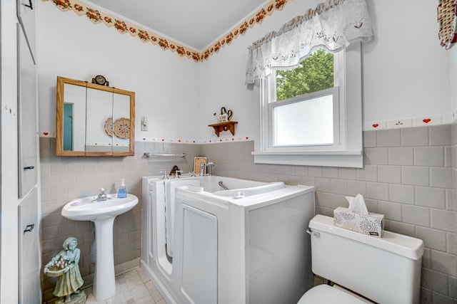 629 S Union St, Aurora, IL 60505 - full bathroom featuring tile walls, washer and dryer, a garden tub, toilet, and wainscoting