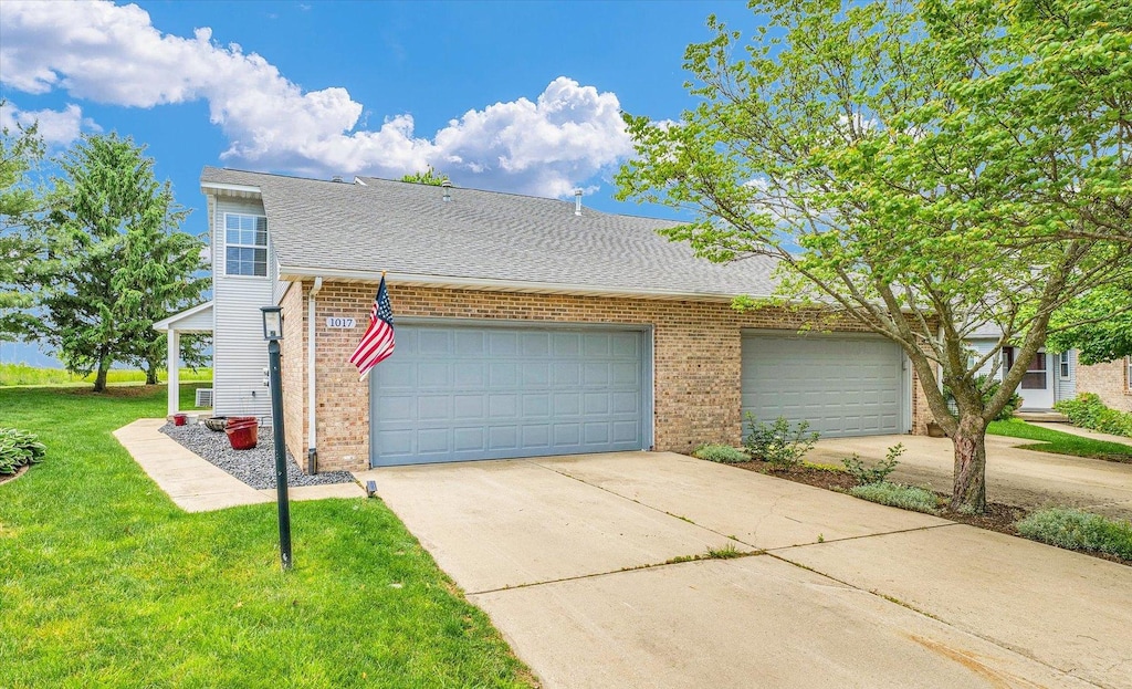 1017 Pheasant Cir, Savoy, IL 61874 - townhome / multi-family property with brick siding, driveway, a front yard, a garage, and roof with shingles