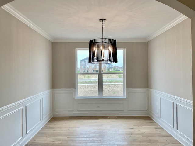 LOTT315929 Prairie View Ct, New Lenox, IL 60451 - empty room featuring light wood-style floors, a chandelier, arched walkways, wainscoting, and crown molding