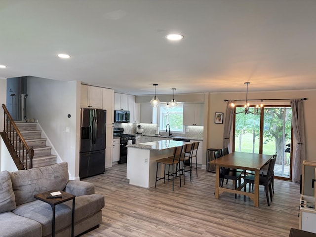 1487 Kathleen Way, Elk Grove Village, IL 60007 - kitchen featuring black appliances, open floor plan, a kitchen island, white cabinetry, and decorative backsplash