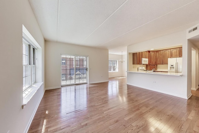 200 N Addison Ave Unit 306, Elmhurst, IL 60126 - unfurnished living room with light wood-style floors, a chandelier, baseboards, and a textured ceiling