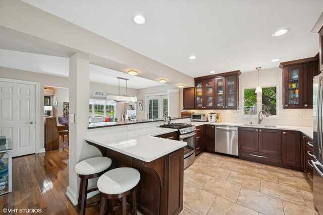 640 Yardley Ln, Hoffman Estates, IL 60169 - kitchen featuring appliances with stainless steel finishes, a sink, a peninsula, a kitchen bar, and backsplash