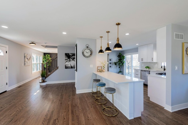 22W046 Mccormick Ave, Glen Ellyn, IL 60137 - kitchen featuring stainless steel dishwasher, a sink, white cabinets, a kitchen bar, and light countertops